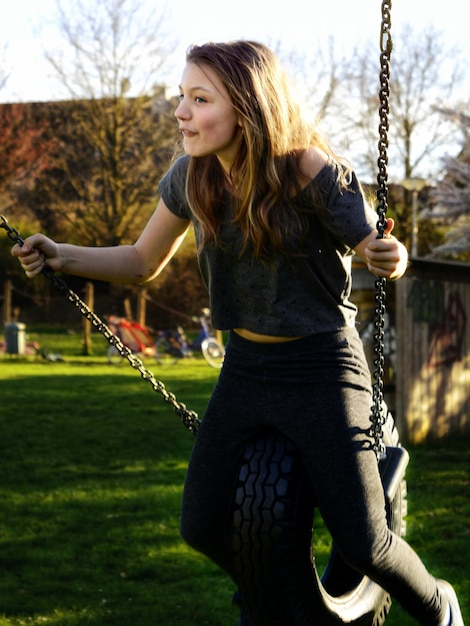 Foto giovane donna sull'altalena nel parco giochi