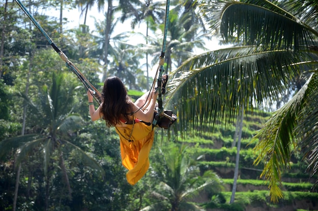 Foto giovane donna che oscilla nella foresta pluviale della giungla di bali indonesia