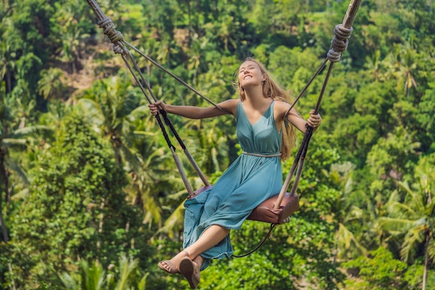 Young woman swinging in the jungle rainforest of Bali island Indonesia Swing in the tropics Swings trend of Bali