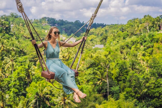 Young woman swinging in the jungle rainforest of Bali island Indonesia Swing in the tropics Swings trend of Bali