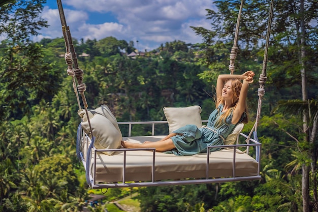 Giovane donna oscillante nella foresta pluviale della giungla dell'isola di bali indonesia oscillazione nei tropici tendenza oscillazioni di bali