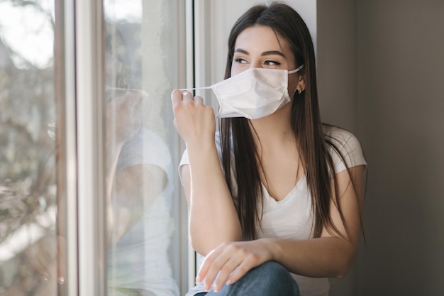 Young woman take off protective mask and use smartphone end of quarantine coronavirus theme
