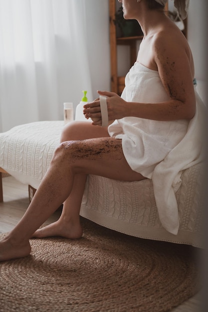 Young woman takes care of her body makes massage with a stiff brush uses an anticellulite body scrub