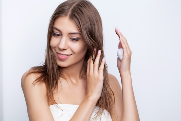 Young woman takes care of her hair using natural oils and conditioners for hair care.