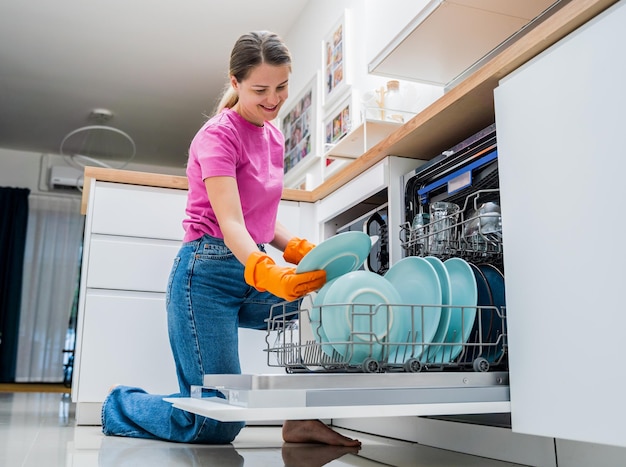 Young woman takes dishes out of the dishwasher machine