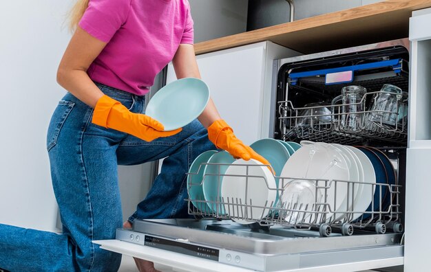 젊은 여성 이 접시 세탁기 에서 접시 를 꺼낸다