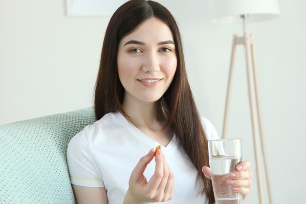 若い女性は家で魚油カプセルを取ります