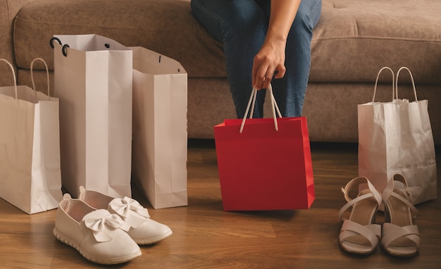 A young woman takes out her purchases from a bag while sitting on the sofa