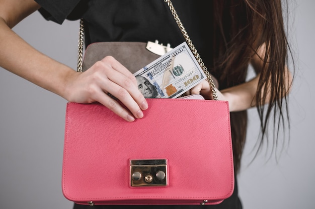 Young woman takes out money from a pink bag