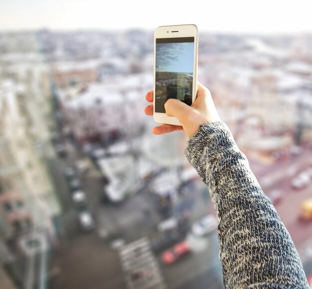 La giovane donna prende una foto di una città dall'alto edificio