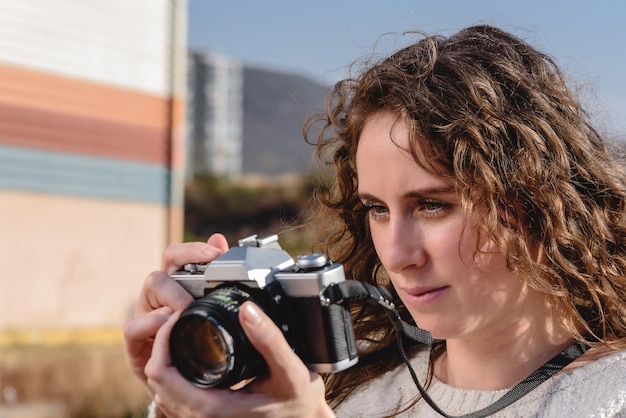 Молодая женщина фотографирует в отпуске с ретро-фотокамерой в поле.
