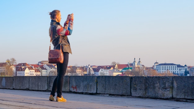 Young woman takes pictures of the city on a smartphone