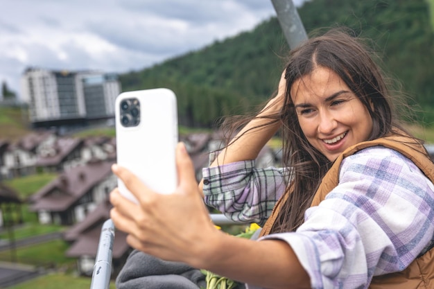 若い女性が山のケーブルカーで自分撮りをします
