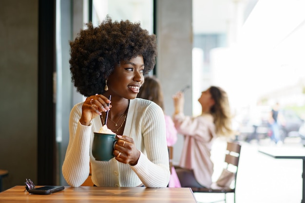 Молодая женщина делает перерыв и пьет кофе в кафе