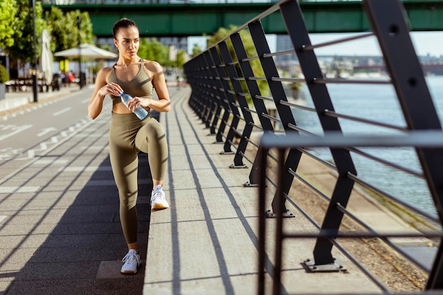 Young woman taking a break during exercise on the river promenade