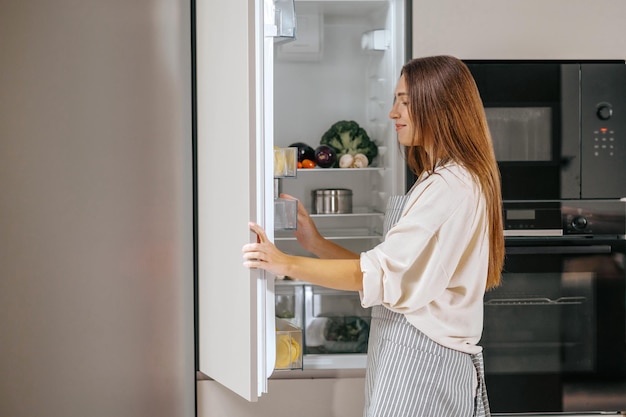 冷蔵庫から食べ物を取る若い女性