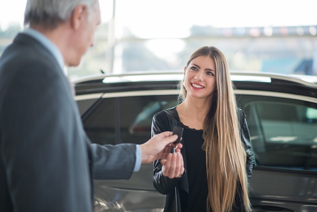 Young woman taking the keys for her car in a showroom