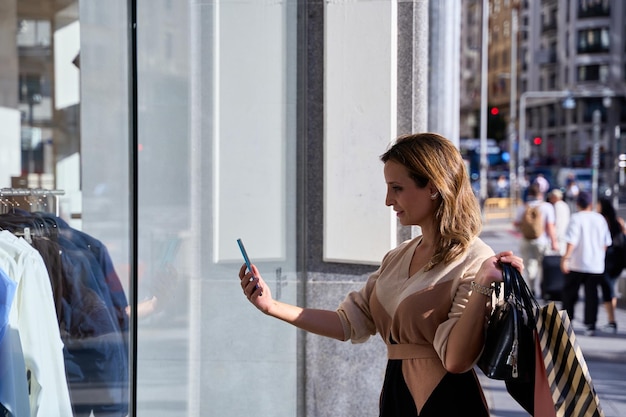 Photo young woman taking a photo through a store window