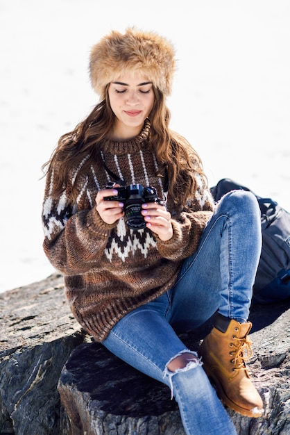 Foto giovane donna che prende le fotografie nelle montagne nevose