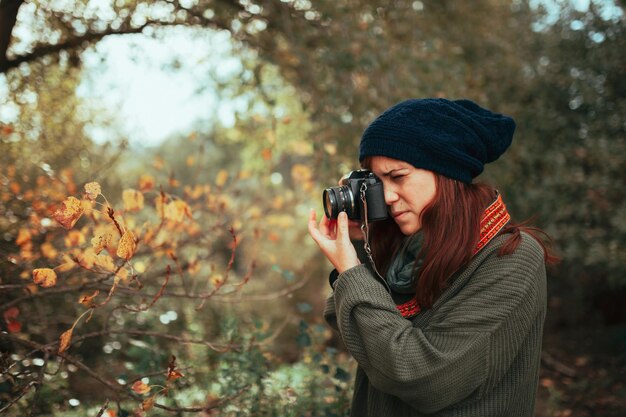 Photo young woman taking photos in the forest with an old analog camera