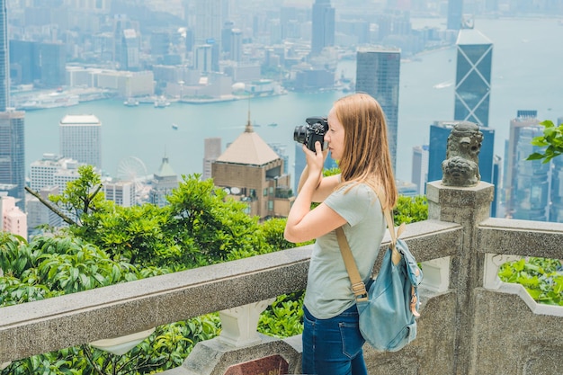 Young woman taking photos of victoria harbor in Hong Kong, China.