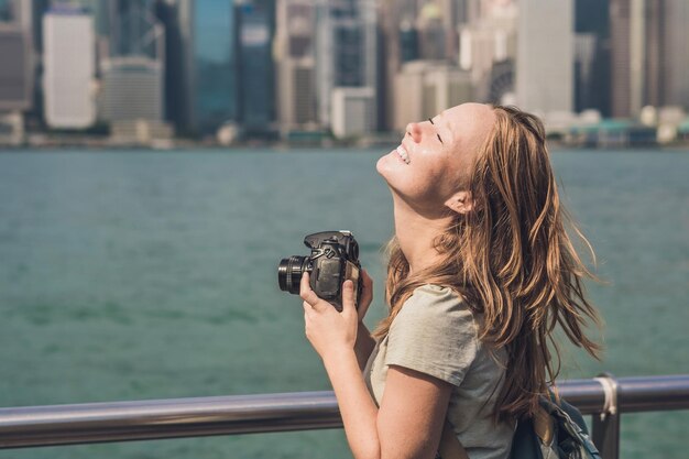 Young woman taking photos of victoria harbor in Hong Kong, China