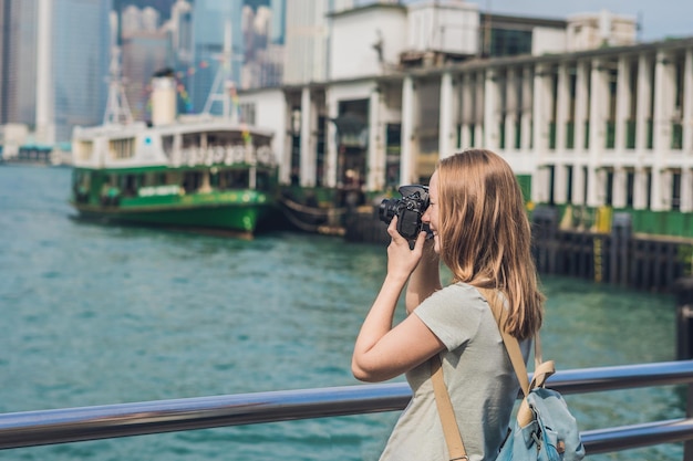 Молодая женщина фотографирует гавань Виктория в Гонконге, Китай