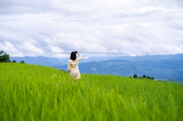 山の風景の写真を撮る若い女性。