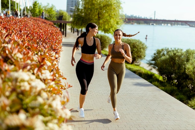 Photo young woman taking running exercise by the river promenade