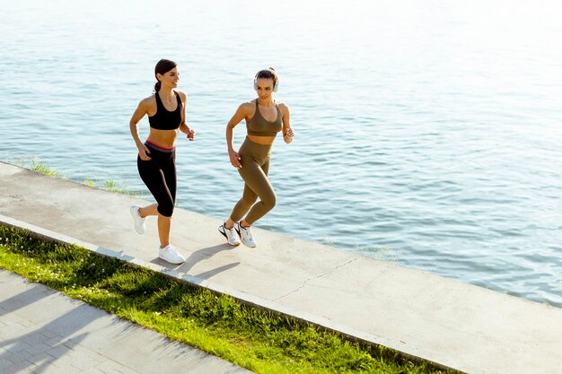 Photo young woman taking running exercise by the river promenade