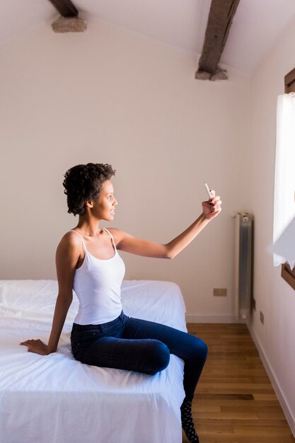 Young woman taking a selfie in bedroom