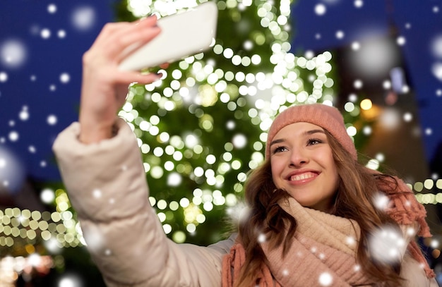 Foto giovane donna che si fa un selfie sopra l'albero di natale