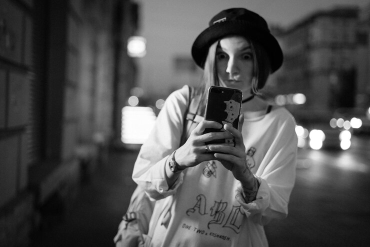 Photo 夜路上で携帯電話からセルフィーを撮る若い女性