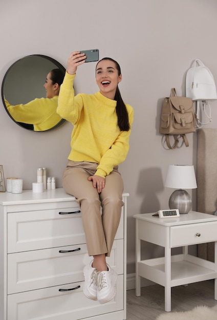 Young woman taking selfie at home in morning