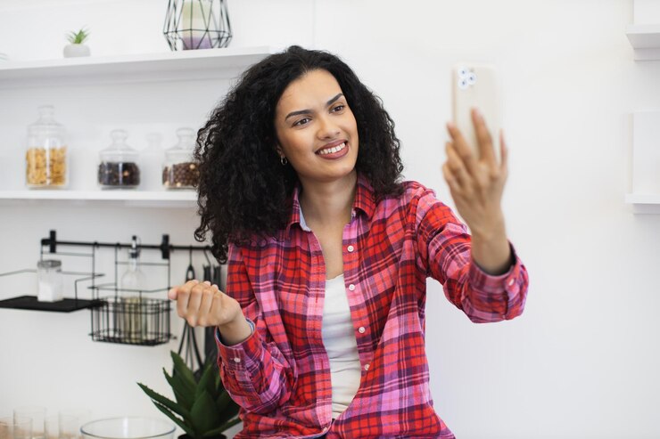 फोटो young woman taking a selfie at home with cheerful expression and casual attire