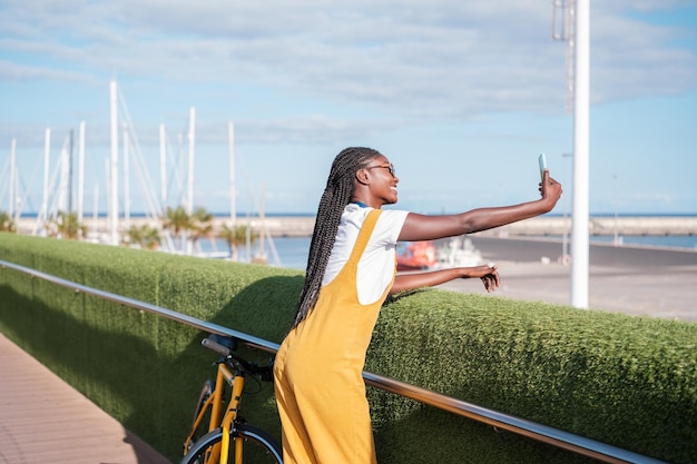 Young woman taking a selfie on a walk by the sea during sunset Concept lifestyle urban style outdoors