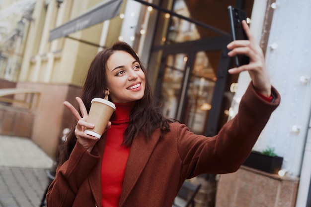 Young woman taking selfies on her cell phone on the street