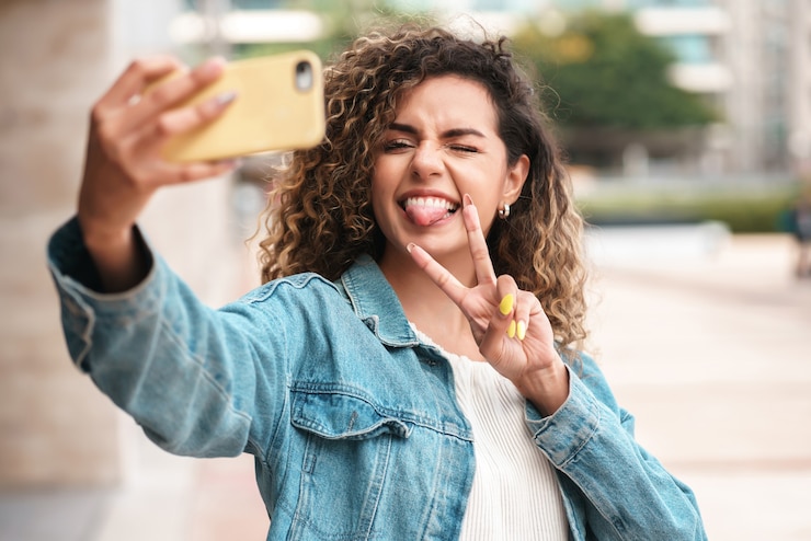 Photo young woman taking selfies with her mophile phone while standing outdoors. urban concept.