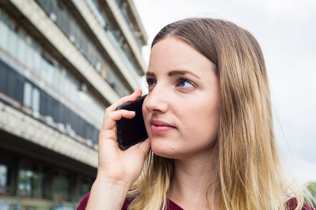 若い女性が彼女の携帯電話で話しています。