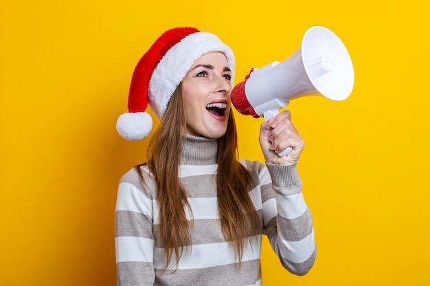 Young woman talking into a megaphone on a yellow background