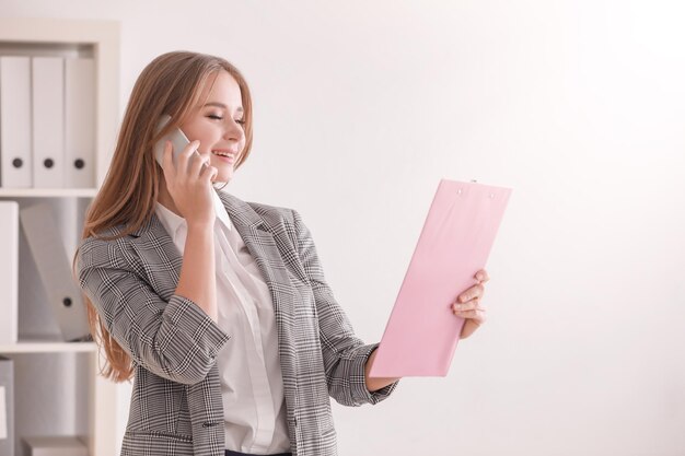 オフィスで携帯電話で話している若い女性