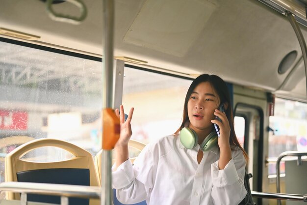 Young woman talking on mobile phone while traveling by bus City life and transportation concept