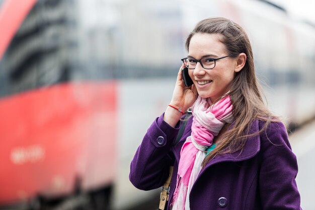 Photo young woman talking on mobile at train station