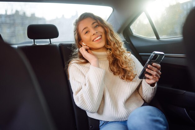 車の後部座席で電話で話している若い女性 ビジネステクノロジーブログコンセプト