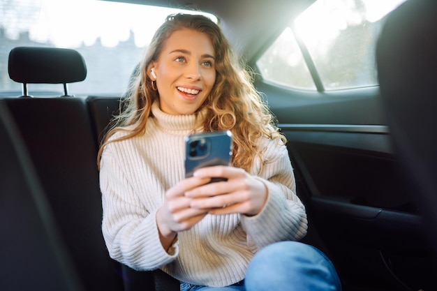 Young woman talking on the phone in the back seat of the car Business technology blogging concept