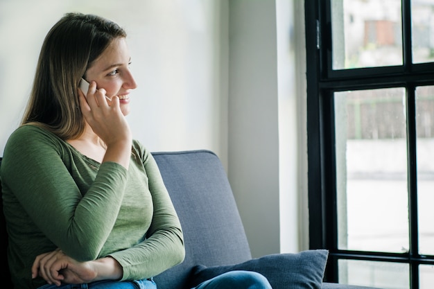 Young woman talking on phone on sofa