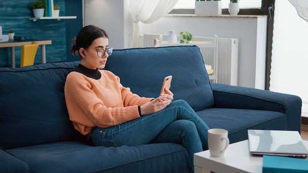 young woman talking on video call sitting on sofa at home