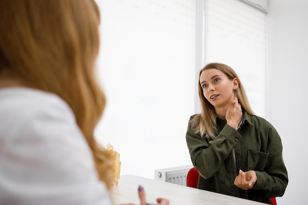 Young woman talking with doctor and having neck pain