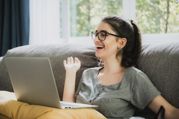 young woman talking with video conference at home, online remote communication technology to call by laptop computer on cyberspace, lifestyle of female person happy to work and keep distant isolated