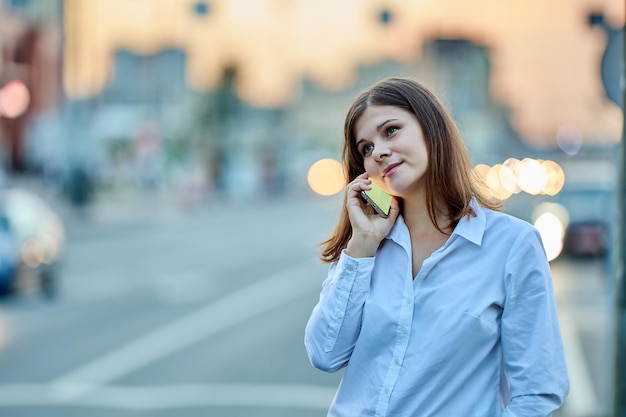 Young woman talks by handy on traffic street